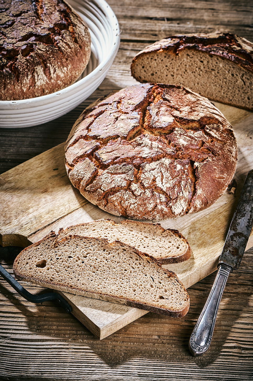 Römerkruste auf Holzbrett mit angeschnittenen Scheiben, rustikale Krume und kräftige Kruste.