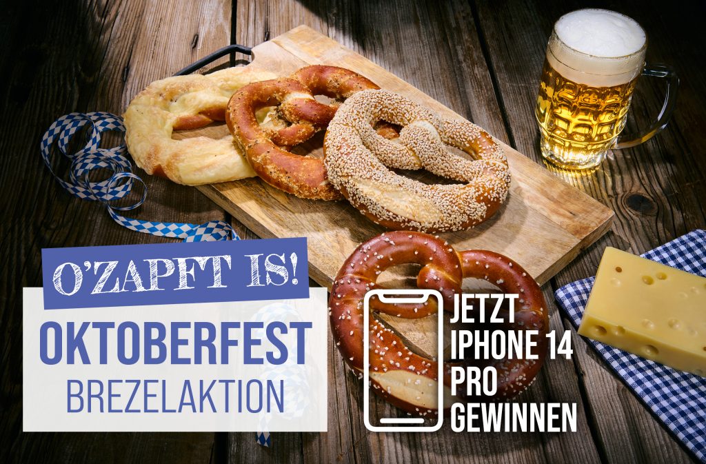 Oktoberfestbrezeln mit Bier, Käse und iPhone-Gewinnspiel-Aktion auf Holzbrett.
