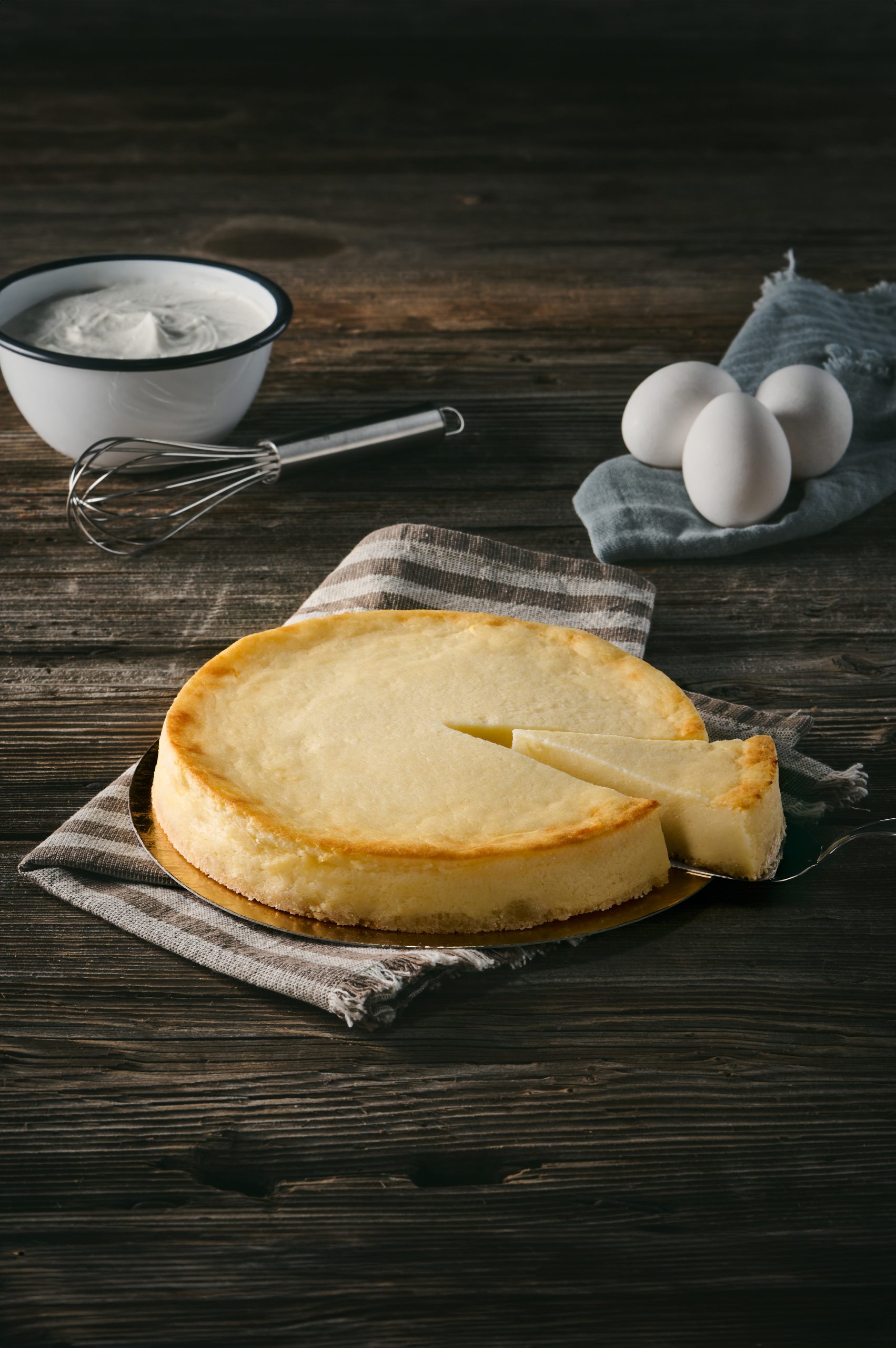 Leichter Käsekuchen auf Holzbrett mit herausgehobenem Stück